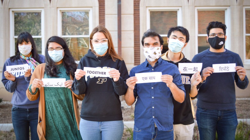 Students holding signs that read Together in their native language.